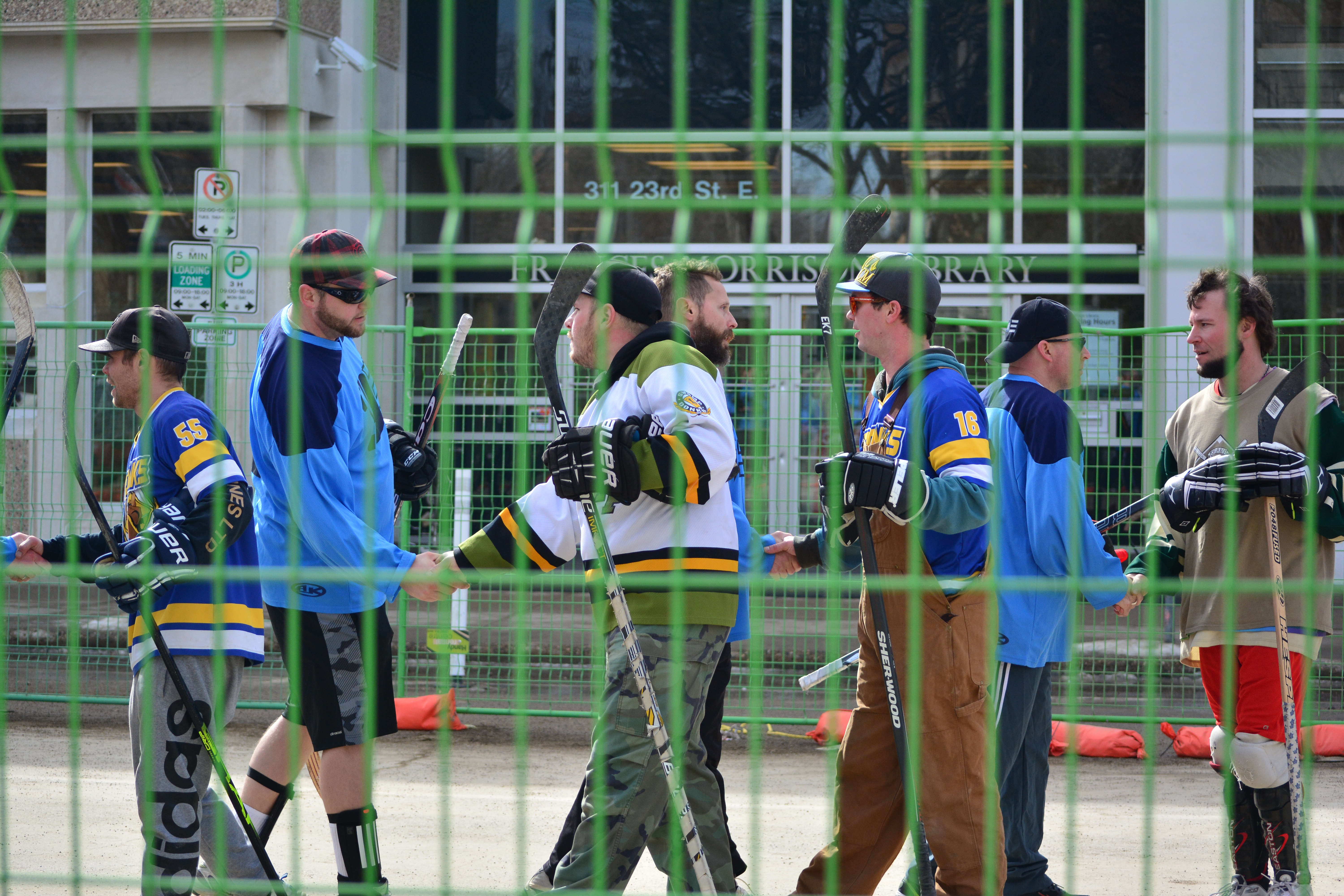 Dynamo employees in road hockey gear in a line shaking the hands of the opposing hockey team.