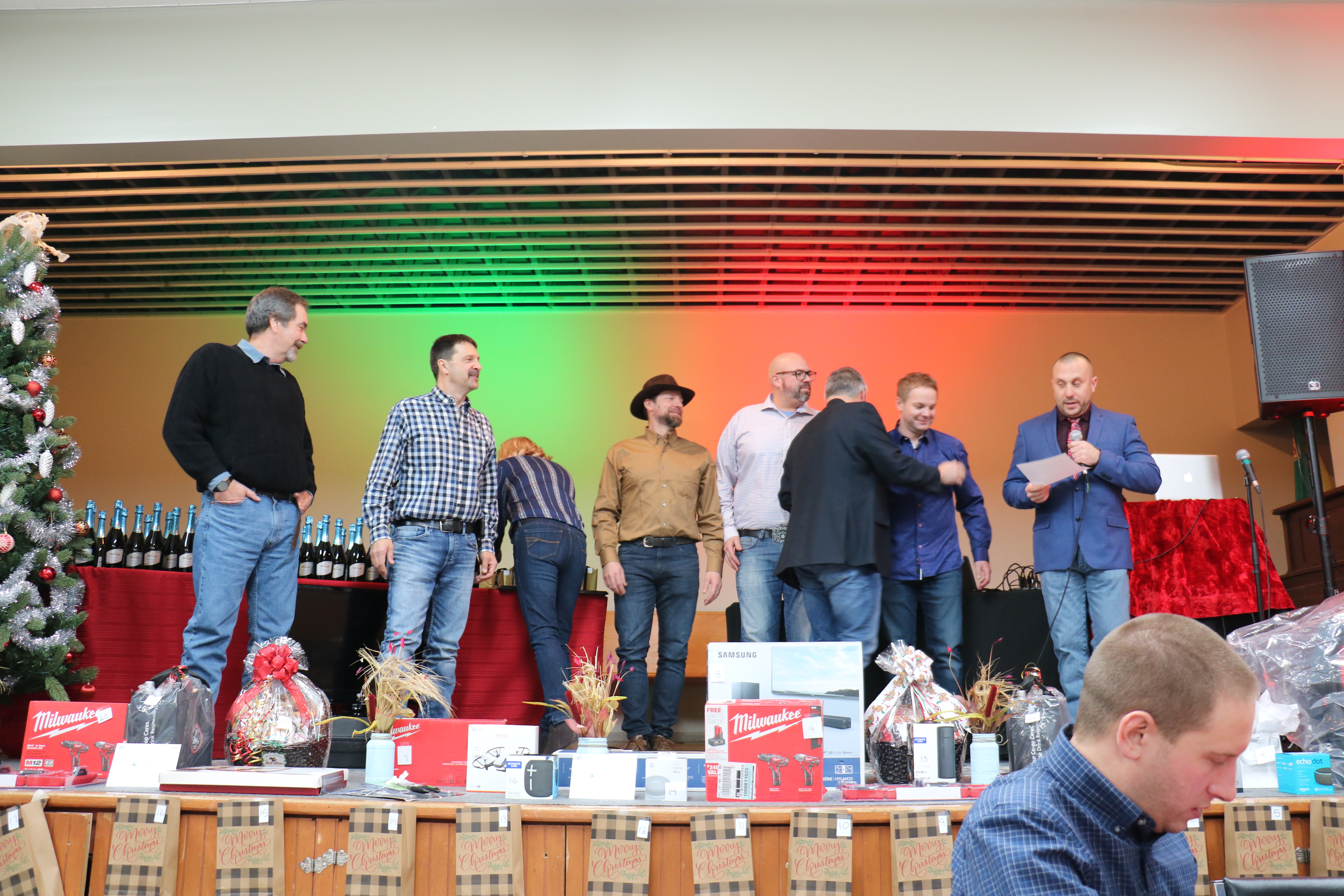 Doug Helmeczi with a microphone on stage for Dynamo Christmas party.