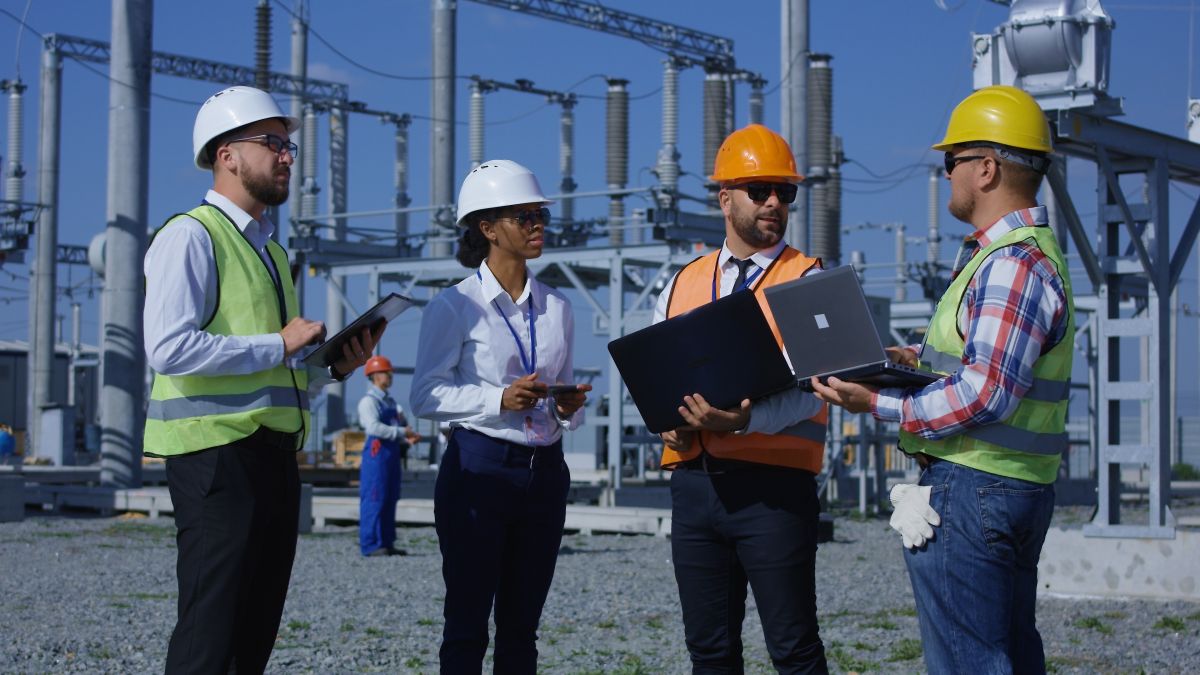 Four Dynamo project managers at substation reviewing computers. All are wearing Personal Protective Equipment 