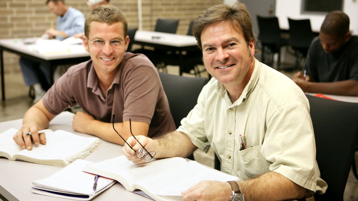 Two employees in a classroom smiling as they take Qualified electrical worker training QEW.