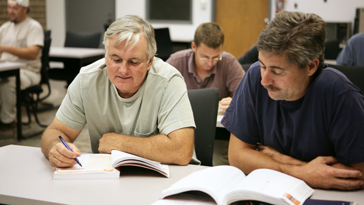 Two employees in a classroom smiling as they take non-electrical worker arc flash awareness training.